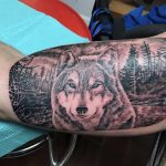 See how realistic shading, natural scenery, and thoughtful composition come together in a detailed black and grey wolf tattoo from Elite Ink.
